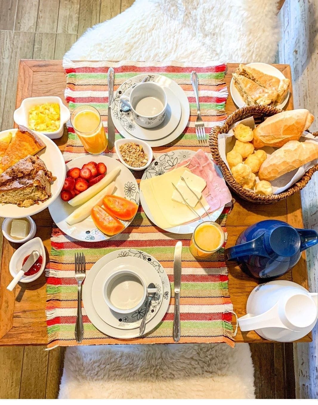 Café da manhã completo com pães, frutas e sucos